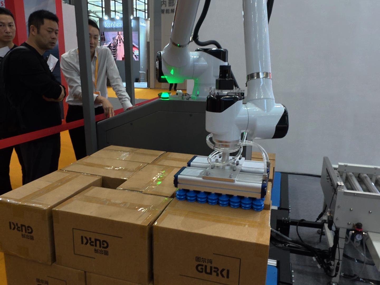 Collaborative robot arm handling packaged goods at an industrial automation exhibition in China